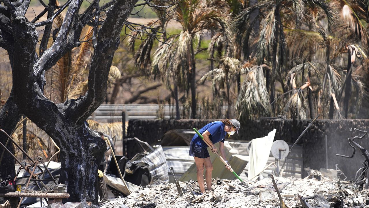 A woman digs through rubble of a home destroyed by a wildfire on Friday, Aug. 11, 2023, in Lahaina, Hawaii.