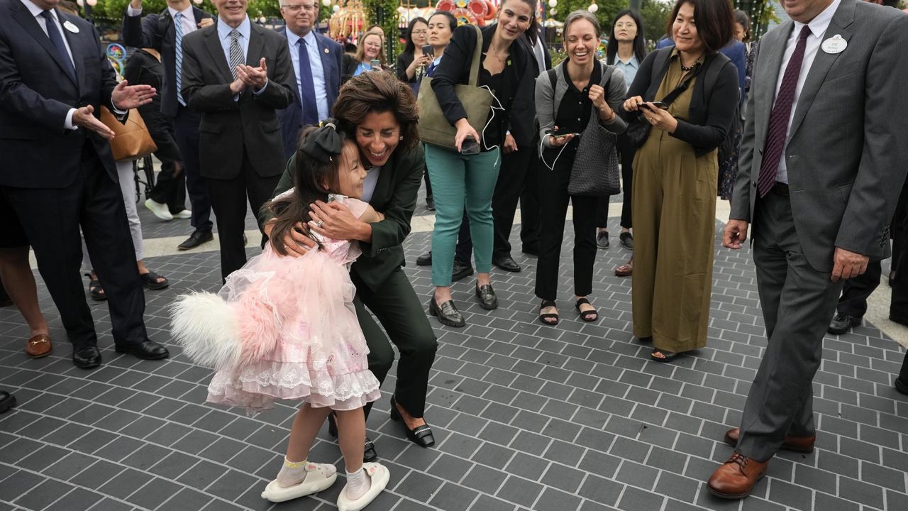 Raimondo hugs a young girl while touring Shanghai Disneyland.